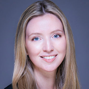 A person with long blonde hair and a light complexion, perhaps seeking the support of group counseling, is smiling at the camera against a plain background.