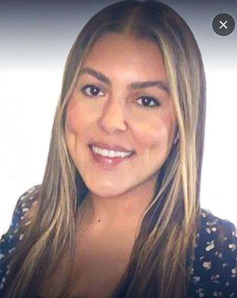 A woman with long, straight hair and a patterned top smiles at the camera, embodying the warmth often found in group counseling sessions.