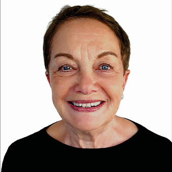 A woman with short hair, representing a renowned mental health clinic, smiles at the camera against a white background, wearing a black top.